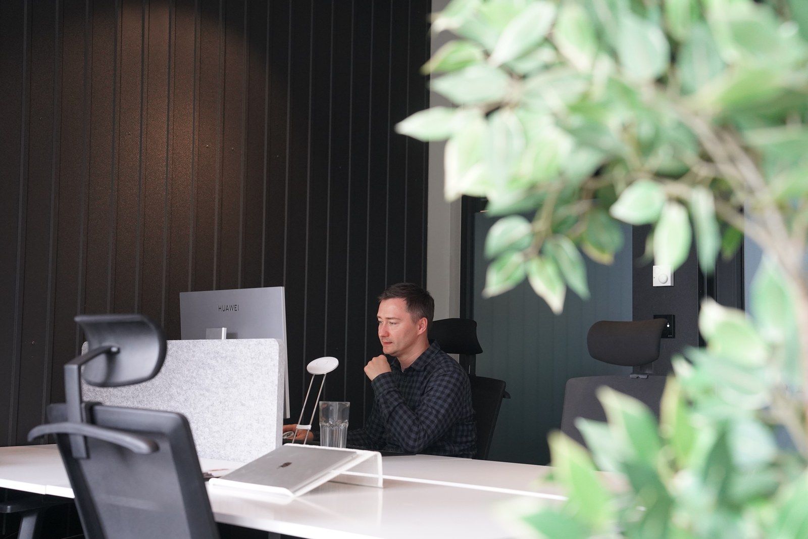 A team member focused on his laptop at a white desk in the office