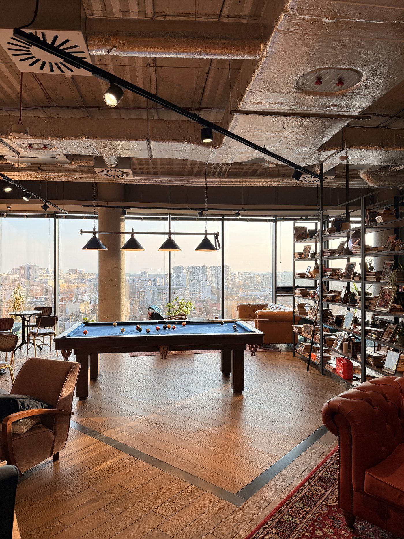The DesignMe office in Gdańsk: a pool table, leather armchairs and bookshelves in front of a wall of windows