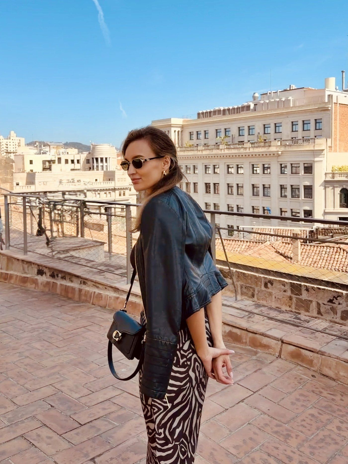 A DesignMe team member on a sunlit rooftop terrace overlooking an old town
