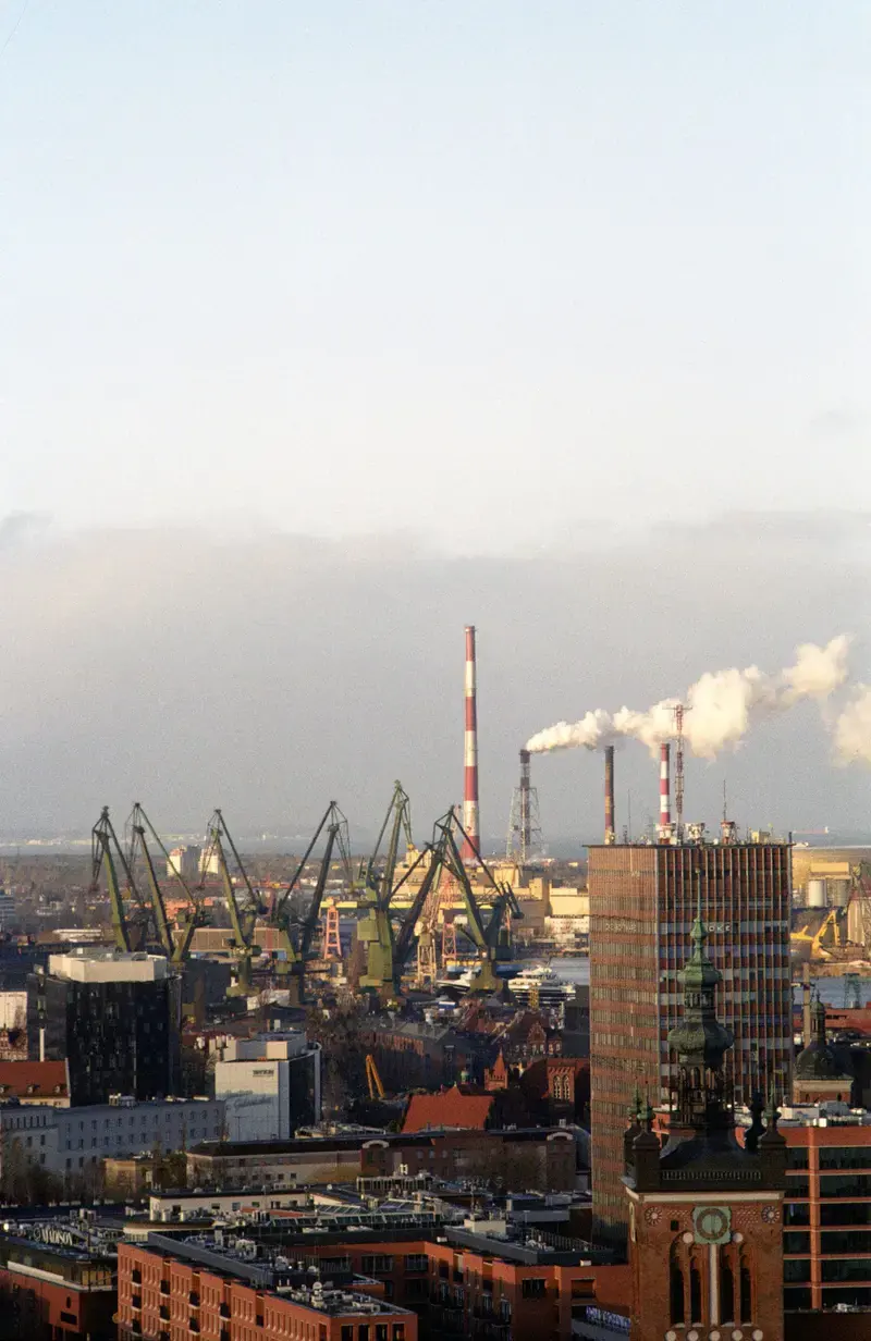 Cranes and chimneys of the Gdańsk shipyard over the city